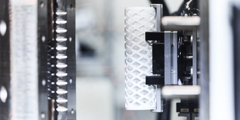 Nahaufnahme eines industriellen Prozesses mit metallischer Struktur und zylinderförmigem Objekt.